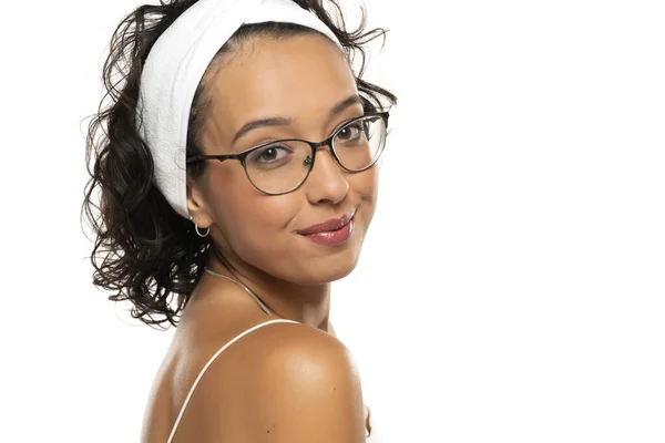 年轻的黑皮肤 面带微笑的女人 戴着化妆品 头带和眼镜 摆出一副白色画室的样子 — 图库照片