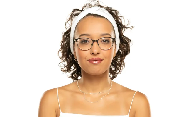 年轻的黑皮肤 面带微笑的女人 戴着化妆品 头带和眼镜 摆出一副白色画室的样子 — 图库照片