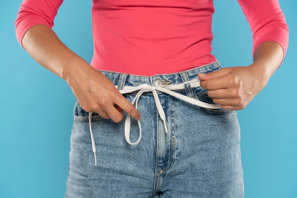 Primer Plano Mujer Aprieta Cinturón Cuerda Jeans Sobre Fondo Azul — Foto de Stock