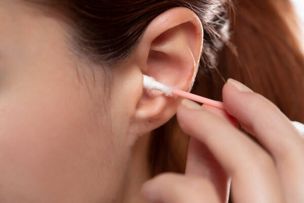 Young woman cleaning ear with cotton swab , closeup.