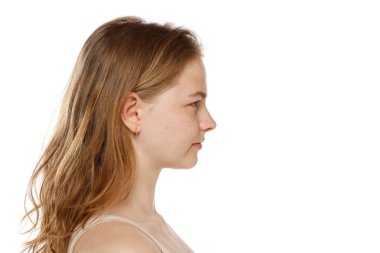Beyaz stüdyo arka planında makyajı olmayan güzel sarışın bir kadının profil portresi.