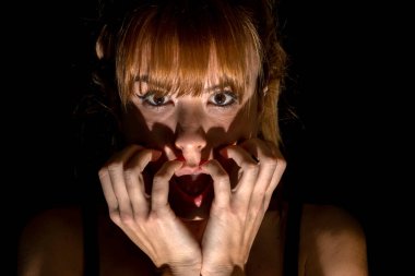 Karanlıktaki korkmuş genç bir kadının portresi.