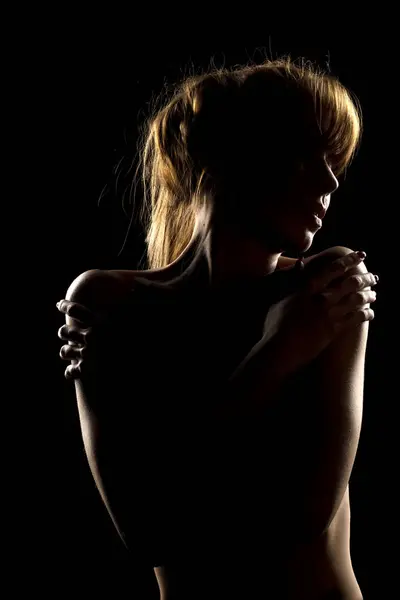 Silhueta Uma Jovem Mulher Tocando Seus Ombros Fundo Estúdio Preto — Fotografia de Stock