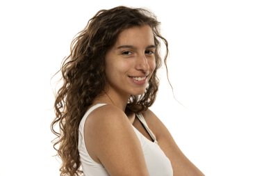 Makyajsız gülümseyen genç bir kadının portresi ve beyaz stüdyo arka planında uzun dalgalı saçlar.