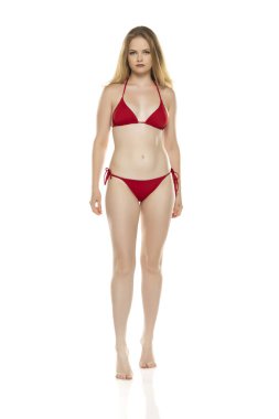 Tüm vücut, ön manzara. Bikinili sarışın kadın beyaz stüdyo arka planında poz veriyor.