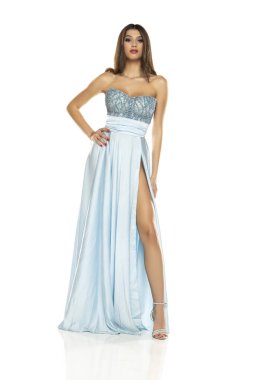 Beyaz stüdyo arka planında izole edilmiş, moda mavisi gece elbisesi giyen zarif, zarif esmer kadın.