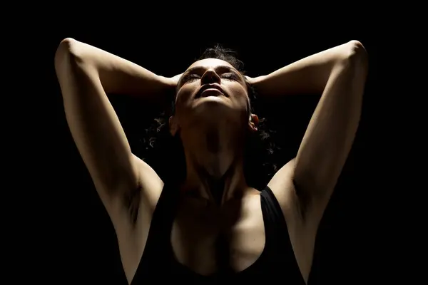 Portrait of a woman in the shadow, hold her head , closed eyes on a black studio background