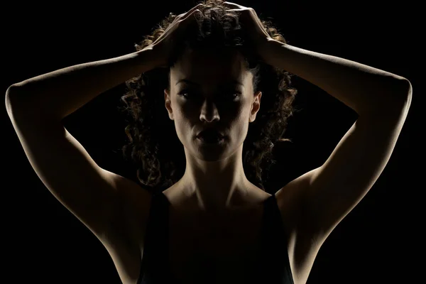 Portrait of a woman in the shadow, hold her head , closed eyes on a black studio background