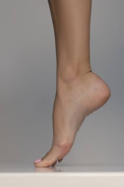 Sağlıklı, güzel kadın ayaklarının yakın çekimi. Sağlık ve güzellik konsepti. Gri stüdyo arka planında insan ayağının yan görüntüsü
