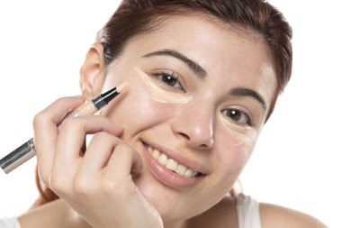 Kusursuz cildine kapatıcı süren, makyaj yapan bir kadın. Kız göz altına düzeltici koymuş. Güzel yüz, cilt bakımı.