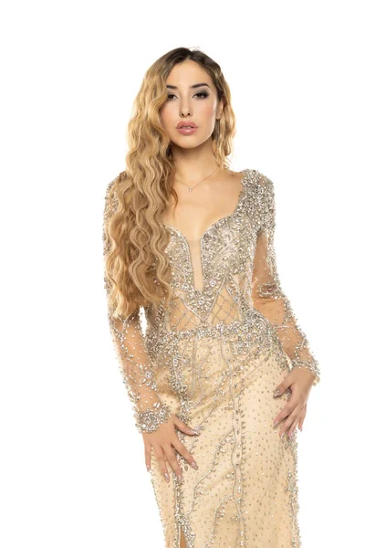 Beyaz stüdyo arka planında poz veren uzun ve zarif elbiseli güzel bir kadın.