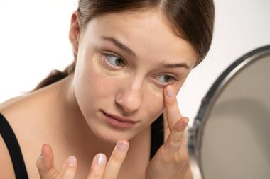 Kusursuz cildine kapatıcı süren, makyaj yapan bir kadın. Kız göz altına düzeltici koymuş. Güzel yüz, cilt bakımı.