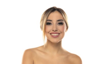 Güzel, gülümseyen sarışın bir kadının portresi. Makyajlı ve saçları beyaz stüdyo arka planında.