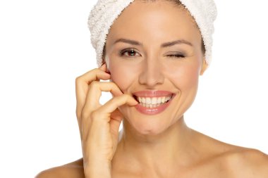 Neşeli, yarı çıplak bir kadının güzel portresi. Kafasına havluyla sarılmış, dişlek bir gülümseme ve beyaz stüdyo arkaplanından izole edilmiş kameraya bakıyor.