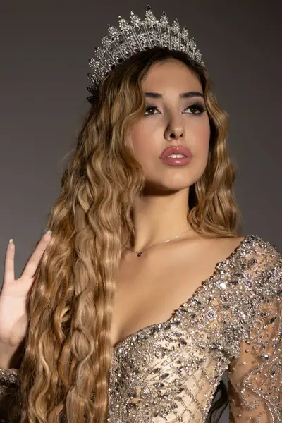 Gri stüdyo arka planında poz veren uzun ve zarif elbiseli güzel bir kadın.