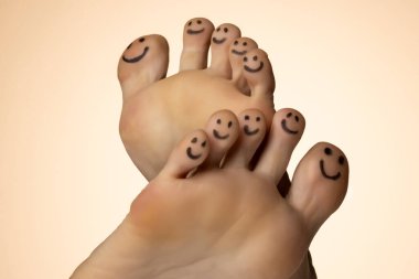 Bej renkli stüdyo arka planında kadın ayağı ve gülümseme çizilmiş.