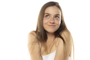 Beyaz bir stüdyoda makyajsız gülümseyen genç bir kızın portresi.