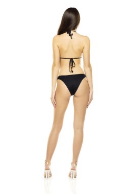 Bikini mayo giymiş esmer bir kadın beyaz stüdyo arka planında poz veriyor. Geri, arka plan.
