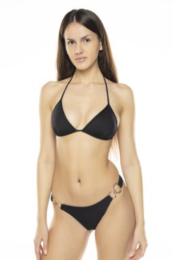 Bikini mayo giymiş esmer bir kadın beyaz stüdyo arka planında poz veriyor. Ön görünüm.