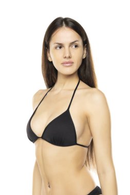 Beyaz stüdyo arka planında poz veren, bikinili, esmer bir kadın. Ön görünüm.