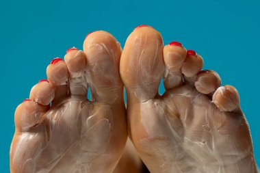 Mavi stüdyo arka planında ayak maskesi olan kadın tabanları.