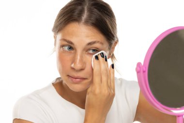 Beyaz bir stüdyoda makyajını silen genç bir kadının portresi.