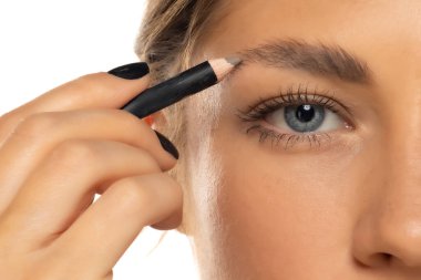Kaş bakımını yakından yap. Beyaz stüdyo arka planında kaş şekillendirme yapan hoş bir genç kadın.