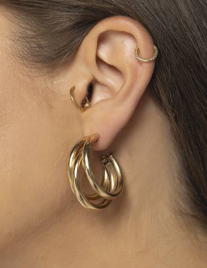 Güzel, lüks bir küpe ve piercing takan bir kadın kulağının yakın çekimi.