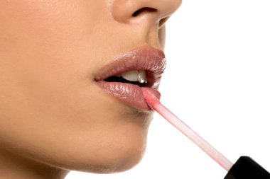 Dudak parlatıcısı süren bir kadın dudaklarına parlak bir son eklemek için dudak parlatıcı kullanan bir kadın, süreci detaylıca yakalıyor.