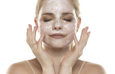 Yüzünde maskeyle poz veren güzel bir genç kadın. Cilt bakımı ve tedavisi, spa, doğal güzellik ve kozmetoloji konsepti.