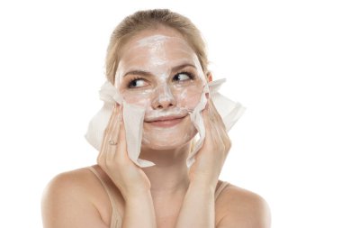 Yüzündeki maskeyi çıkaran güzel, mutlu genç bir kadın. Cilt bakımı ve tedavisi, spa, doğal güzellik ve kozmetoloji konsepti.