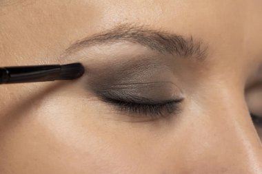 Kadın fırçayla göz farı kullanıyor.