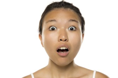 Beyaz stüdyo arka planında poz veren güzel ve şaşırmış Asyalı bir kadının portresi.