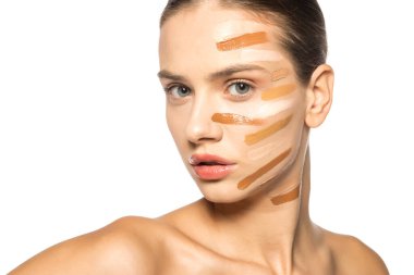 Yüzünde farklı bir sıvı fondöten tonuyla poz veren güzel genç kadın.