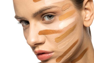 Yüzünde farklı bir sıvı fondöten tonuyla poz veren güzel genç kadın.