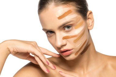 Yüzünde farklı bir sıvı fondöten tonuyla poz veren güzel genç kadın.