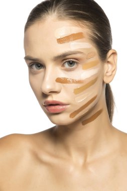 Yüzünde farklı bir sıvı fondöten tonuyla poz veren güzel genç kadın.