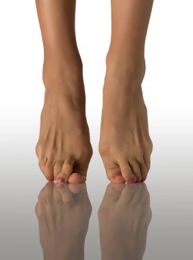 Çıplak ayaklı, beyaz bir stüdyonun arka planında duran bir kadının ön görüntüsü.