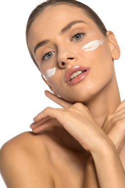 Yüzünde kozmetik ürünüyle poz veren güzel, genç ve şehvetli bir kadın.