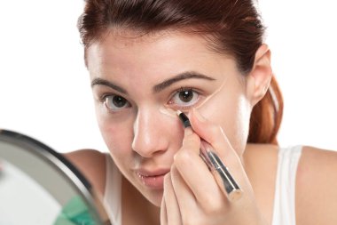 Kusursuz cildine kapatıcı süren, makyaj yapan bir kadın. Kız göz altına düzeltici koymuş. Güzel yüz, cilt bakımı.