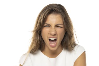 Hafif makyajlı, beyaz bir stüdyoda çığlık atan öfkeli genç bir kadının portresi.