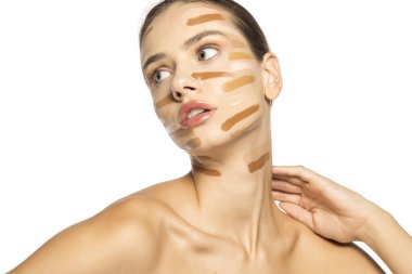 Yüzünde farklı bir sıvı fondöten tonuyla poz veren güzel genç kadın..