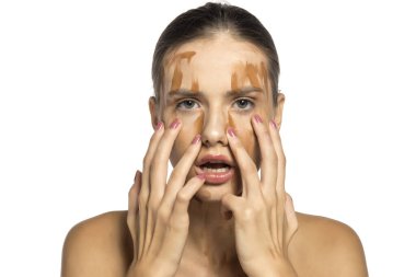 Yüzüne farklı tonlarda sıvı fondöten sürmüş güzel bir genç kadın.