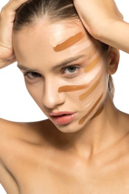 Yüzünde farklı bir sıvı fondöten tonuyla poz veren güzel genç kadın..