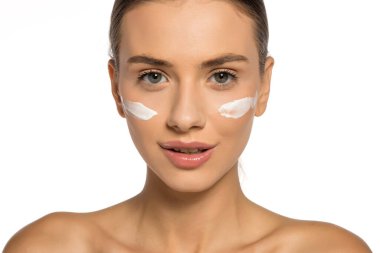 Yüzünde kozmetik ürünüyle poz veren güzel, genç bir kadın.