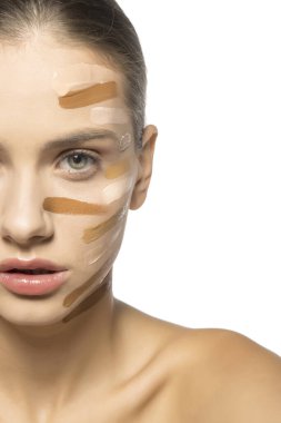 Yüzünde farklı bir sıvı fondöten tonuyla poz veren güzel genç kadın..