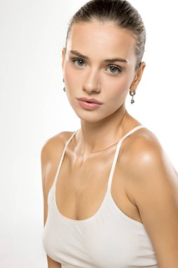 Beyaz bluzlu kadının profesyonel stüdyo portresi, yoğun bakışlar ve incelik, minimalist arka plan..