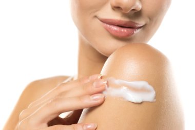 Beyaz cilt kremi sürüp, güzellik ve kendine bakım rutinini vurgulayan bir kadın görüntüsü..