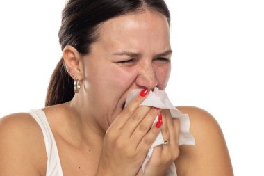 Beyaz stüdyo arka planına ıslak mendille burnunu silen bir kadının portresi.