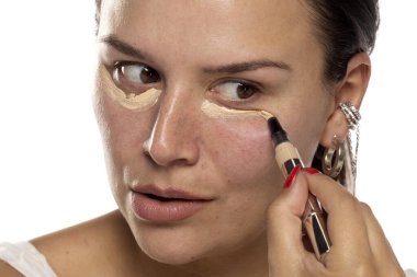 Gözlerinin altına kırmızı çivili bir el ve beyaz arka plana odaklanmış bir ifade uygulayan bir kadın..